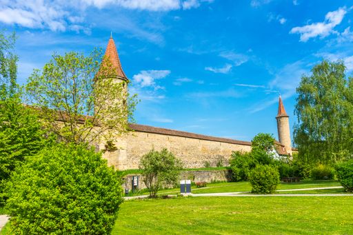 A view of european castle walls with two towers in the green park under the bright blue sky