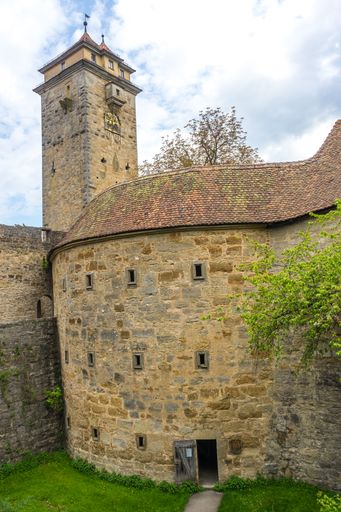 A vertical shot of an old fortress in a park with a tall tower and trees around
