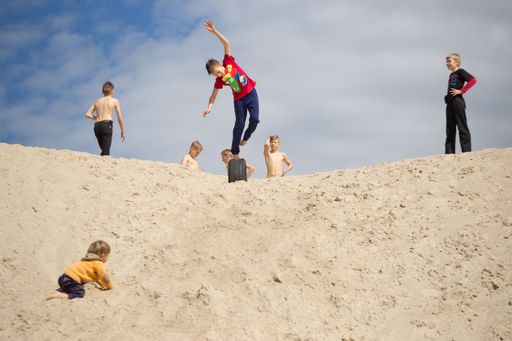 Some children doing parkour on the sand.