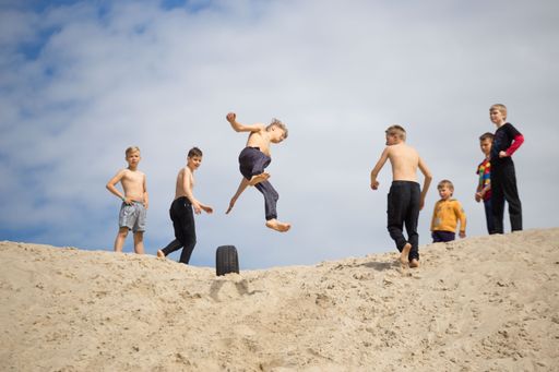 Some children doing parkour on the sand.