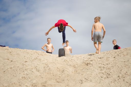 Some children doing parkour on the sand.