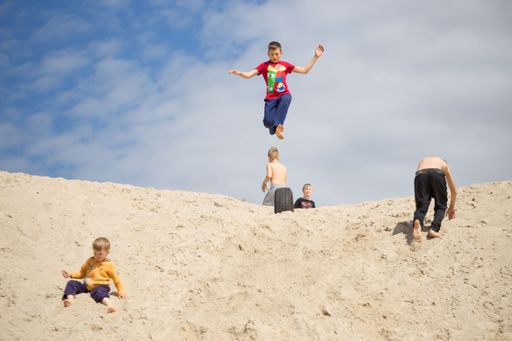 Some children doing parkour on the sand.