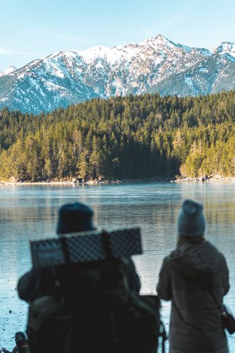 A vertical closeup of two hikers enjoying the beautiful landscape with lake and mountains. Eibsee, Bavaria, Germany.
