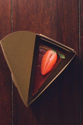 A top view of a Strawberry cheesecake in a triangular cake box