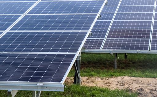 The solar panels in a field covered in greenery under the sunlight at daytime