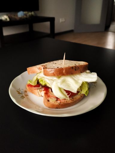 A vertical shot of a sandwich on a plate on a black table