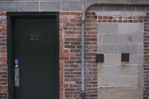 A closeup shot of a dark green door with "22" on it on a brick wall in Columbia, MO