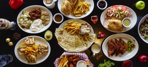 A high angle shot of a table setting with quesadillas, club sandwich, french bread, baguette, chips, french fries, eggs,