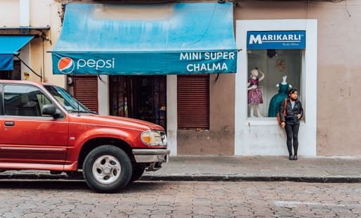 A street photography of young woman smoking a cigarette in front of a shop