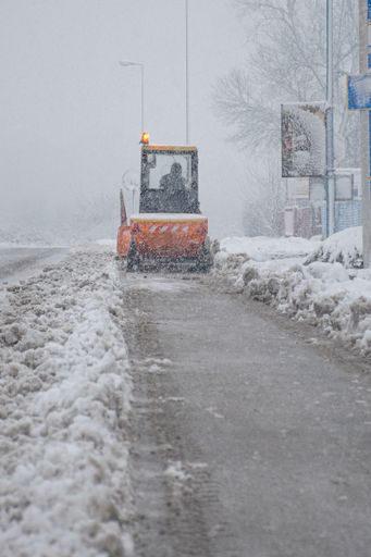 A closeup of trucks cleaning routes while snowing outside