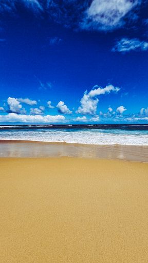 A vertical shot of a beautiful sandy beach under a blue cloudy sky on a sunny day