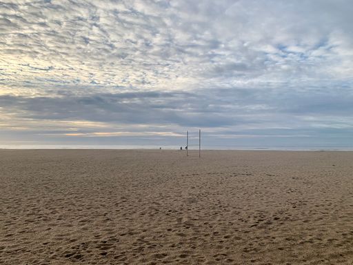 A beautiful view of a sandy beach and seascape against blue cloudy sky at sunrise