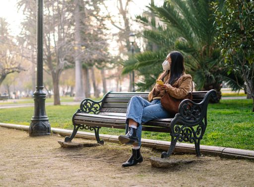 A closeup of a girl sitting on a bench in a park