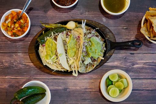 An overhead closeup shot of tacos with sauces on a wooden table