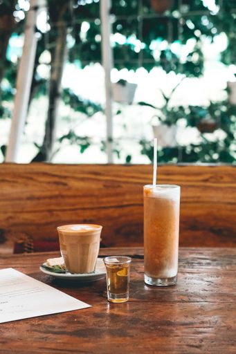 A closeup of a cold and a hot drink on a wooden table at a restaurant