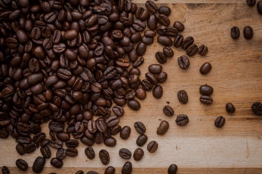 A closeup shot of brown beans of roasted coffee stuffed on a wooden table