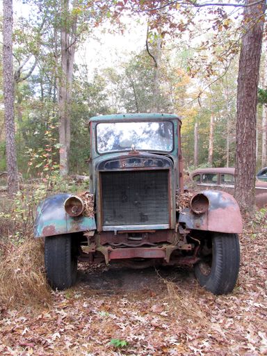 A front view of an old abandoned rusty damaged weathered truck