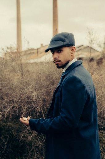 A vertical shot of a Hispanic male in retro 1900s gangster fashion posing