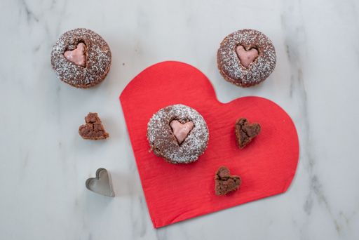 A top view of heart-shaped cupcakes on a red table mat
