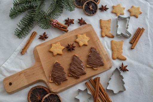 A top view of Christmas ginger cookies with chocolate cream on a wooden cooking board