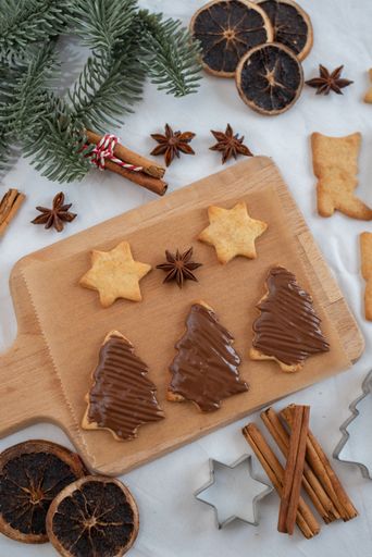 A vertical, top view of Christmas ginger cookies with chocolate cream on a wooden cooking board