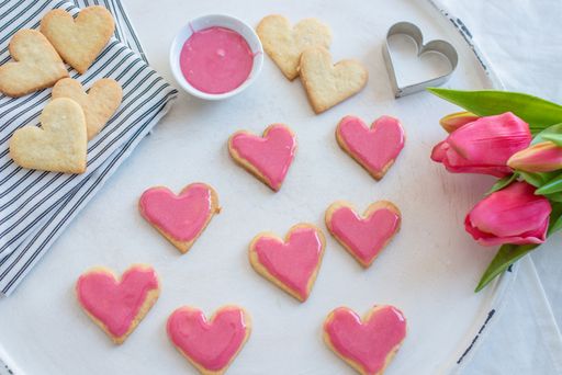 A top view of a bunch of heart-shaped cookies with pink cream