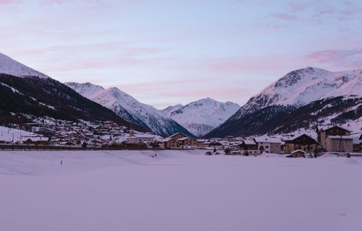 A panoramic view of the ski resort of Livigno with snowy mountains in background at dawn, Italy