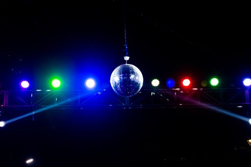 A row of colorful lights falling on a disco ball marking a party ambiance