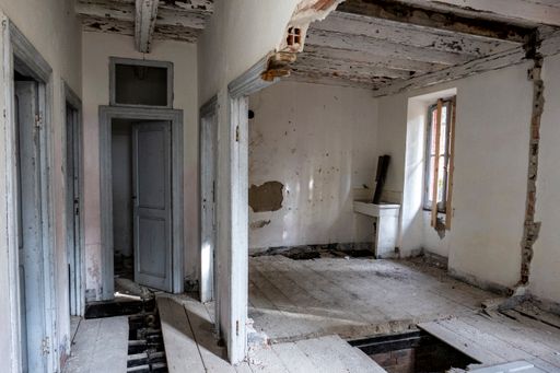 An interior of an old abandoned room with ruined wall and dirty doors