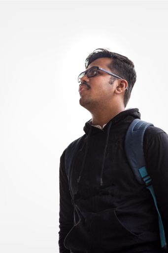 An isolated portrait of a young man wearing glasses looking sideways on a white background