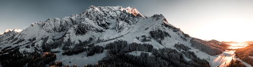 A panoramic shot of rocky mountains covered in the snow under the sunlight in the countryside