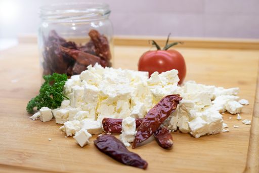 A closeup of white feta cheese, tomato and slices of fried eplant on a wooden table