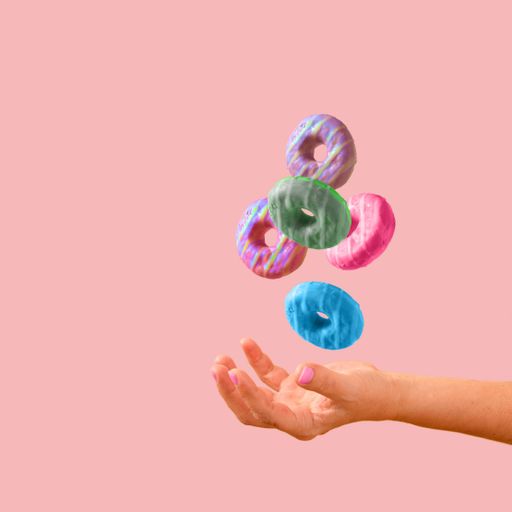 Donuts floating between female hands on a powder pink background