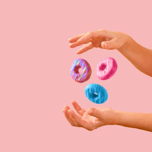 Donuts floating between female hands on a powder pink background
