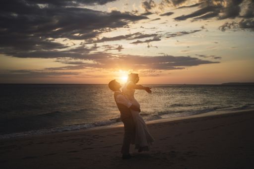 A beautiful horizontal shot of a man hugging a woman on the beach in the evening