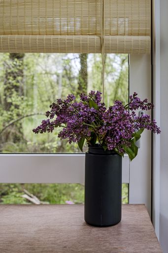 A vertical shot of a vase full of lilac flowers in the room