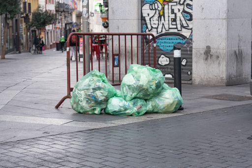Bags of trash piled onto a curb in Madrid, Spain.