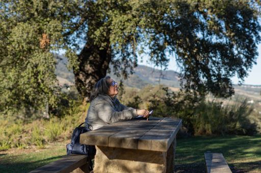 white-haired woman with glasses taking notes in her notebook in the park on a sunny winter's day