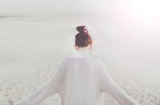 A closeup shot of a young female with arms up on a sandy background