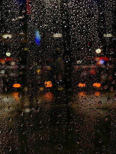 The vertical shot of raindrops on a window after the rain
