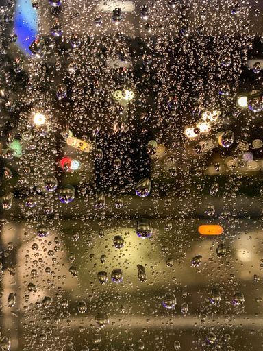 A vertical shot of raindrops on a window after the rain