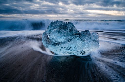 A closeup shot of a glacier lagoon in Iceland with a wavy sea on the background
