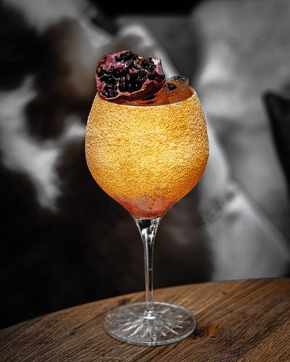 A vertical shot of a gourmet glass of cocktail with pomegranate