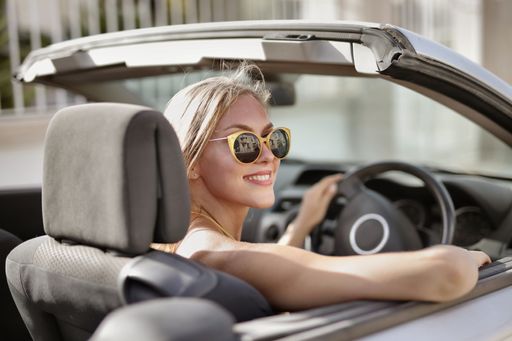 A blonde woman with sunglasses driving a car