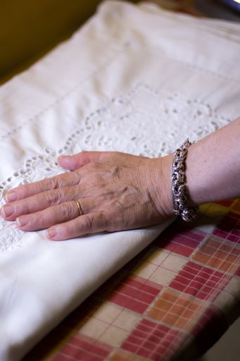 A vertical shot of a woman hand put on a white fabric with patterns