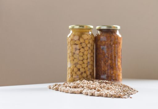 Three jars of non-perishable chickpeas and lentils with spilled seeds on the table purchased for Covid-19 lockdown