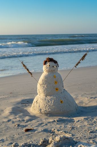 A vertical shot of a snowman made of sand on the beach in Indian Rocks Beach, Florida