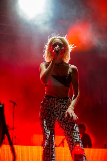 A vertical shot of a portrait of Zara Larsson live at a festival with lights on background