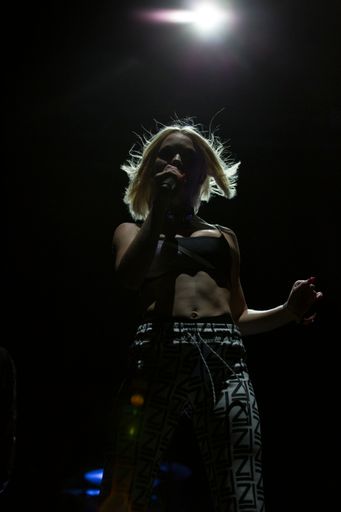 A vertical shot of a portrait of Zara Larsson live at a festival with lights on background