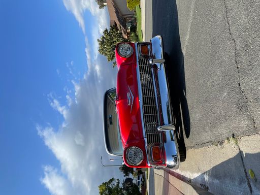 A vertical shot of a red Chevy parked on the street.